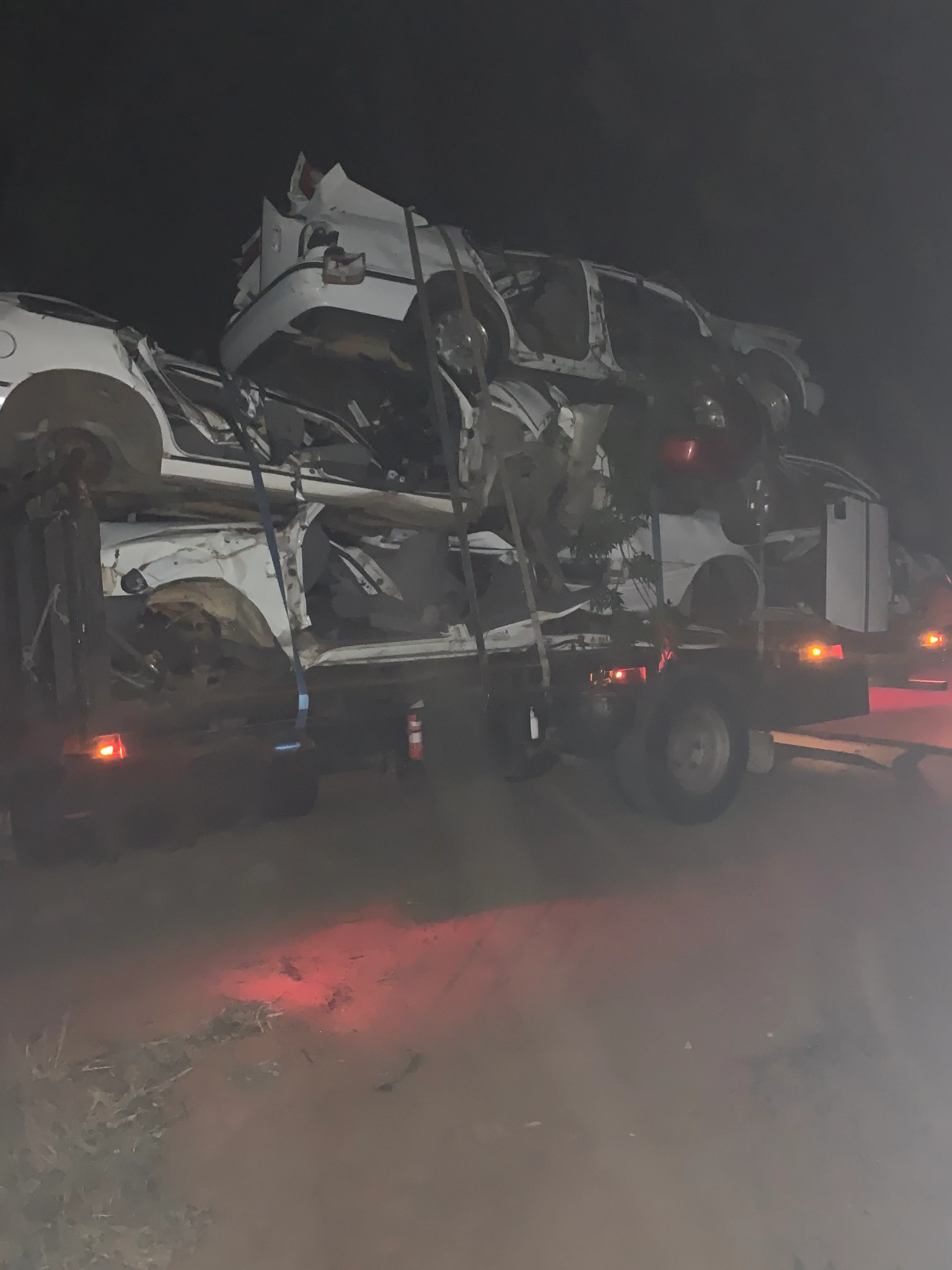 A truck loaded with wrecked cars, photographed at night