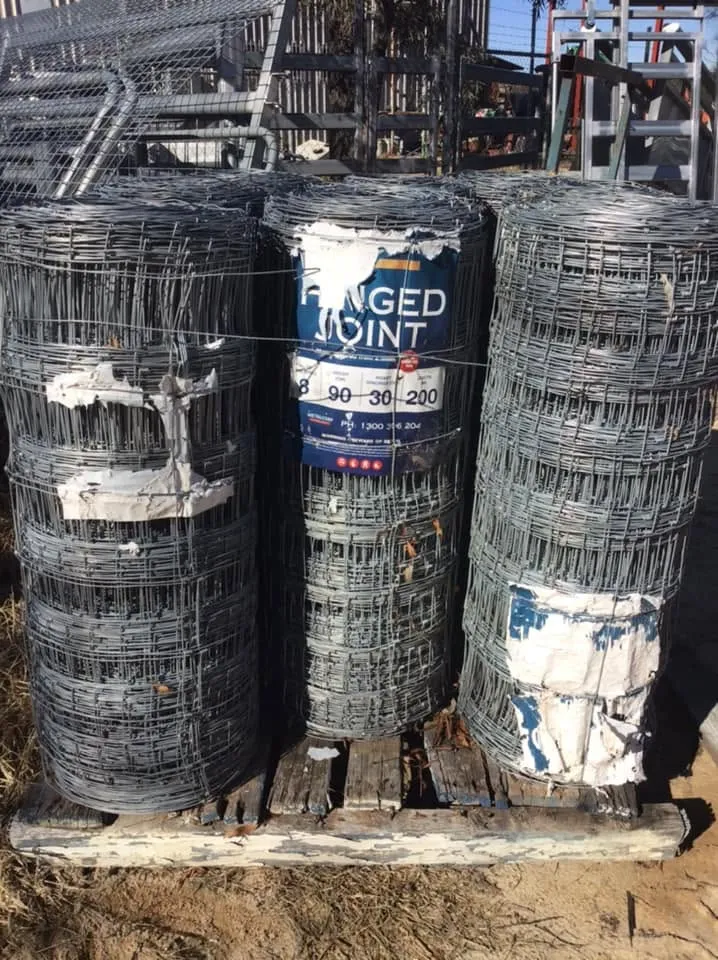Three rolls of hinged-joint fencing wire stacked on a pallet