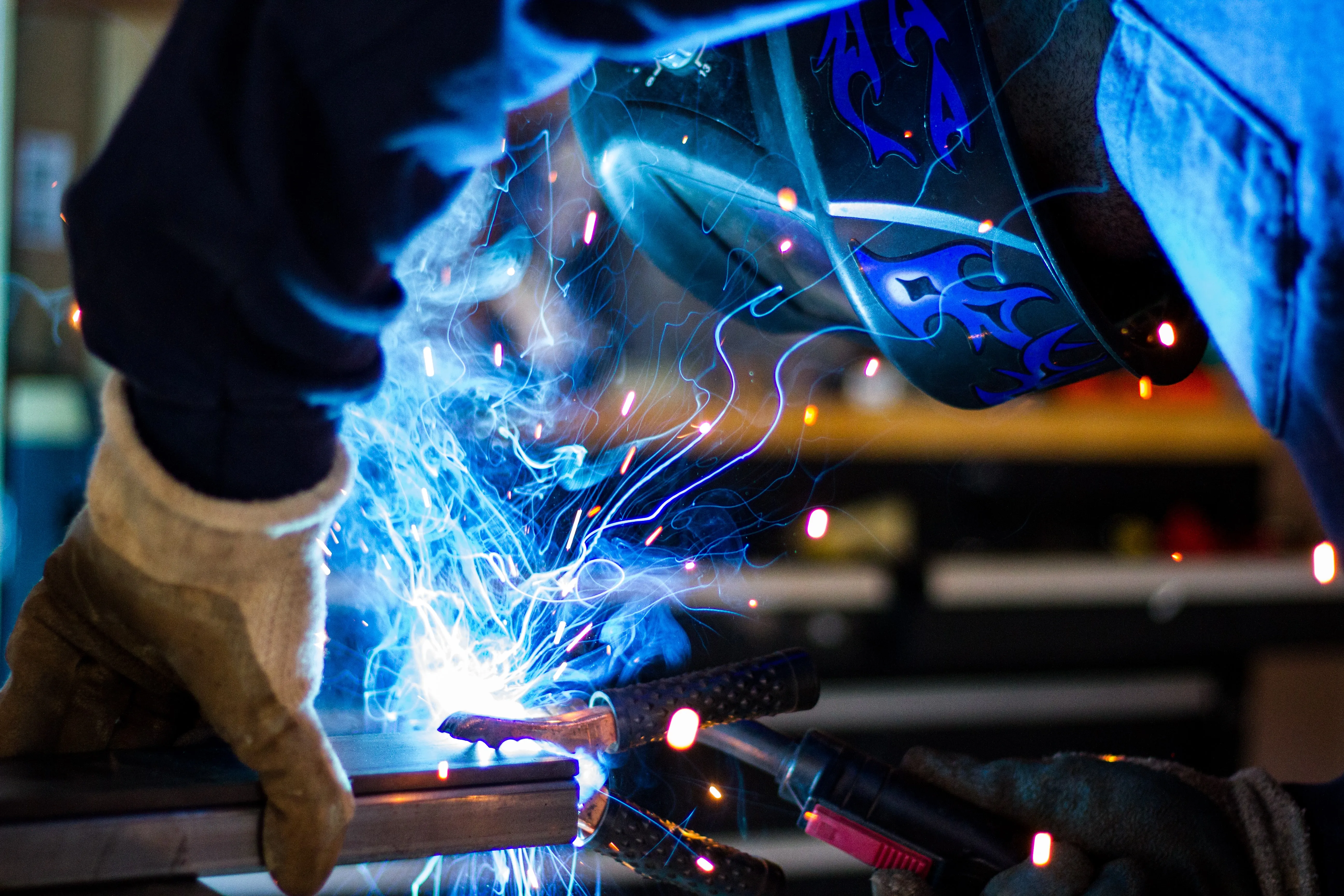 A welder joining steel, sparks flying from the weld